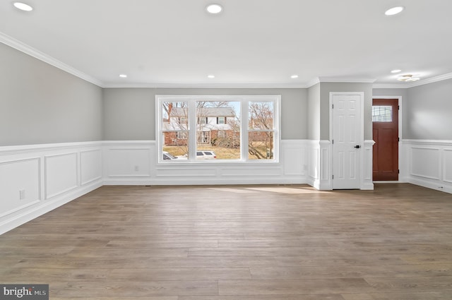 unfurnished living room featuring recessed lighting, wainscoting, and wood finished floors