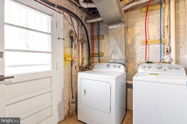 laundry area with a healthy amount of sunlight, laundry area, concrete block wall, and washing machine and clothes dryer