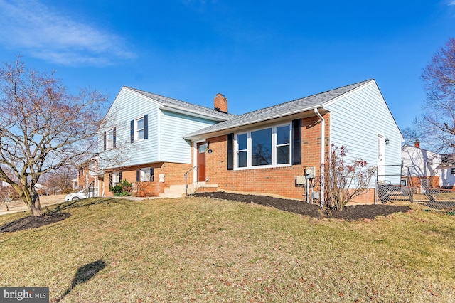 view of front of property featuring entry steps, a chimney, fence, a front lawn, and brick siding