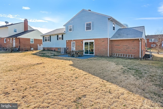 rear view of house with a patio, cooling unit, fence private yard, brick siding, and a yard