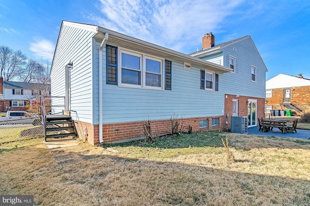 exterior space with central AC unit, a chimney, fence, and a lawn