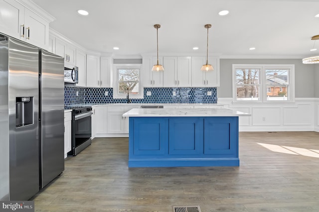 kitchen with stainless steel appliances, white cabinets, crown molding, and wood finished floors