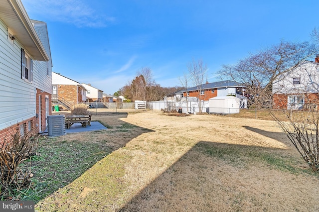 view of yard featuring a residential view, a patio area, a fenced backyard, and central AC unit