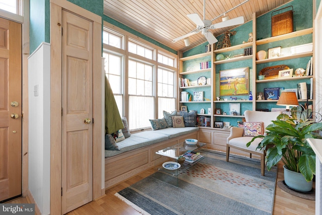 living area with built in features, lofted ceiling, ceiling fan, wood finished floors, and wooden ceiling