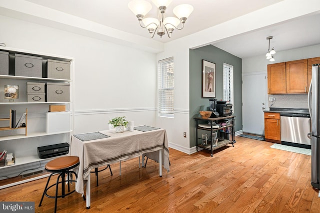 dining room featuring light wood finished floors, a notable chandelier, and baseboards