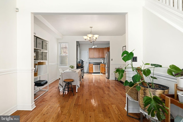 dining space featuring baseboards, a notable chandelier, and light wood-style flooring