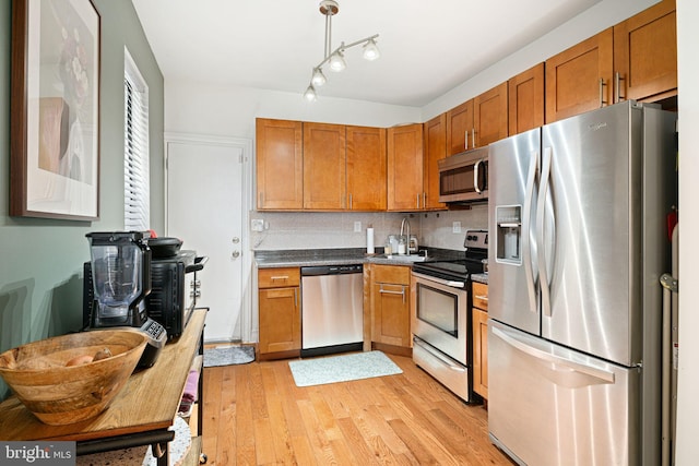 kitchen featuring brown cabinets, stainless steel appliances, light wood-style floors, and a sink