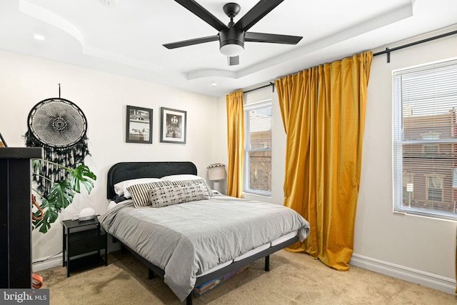 bedroom featuring a tray ceiling, baseboards, and carpet