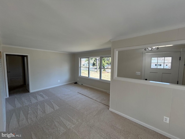 carpeted spare room featuring baseboards and crown molding