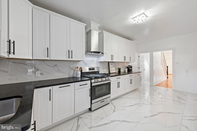 kitchen with white cabinets, decorative backsplash, gas range, marble finish floor, and wall chimney range hood