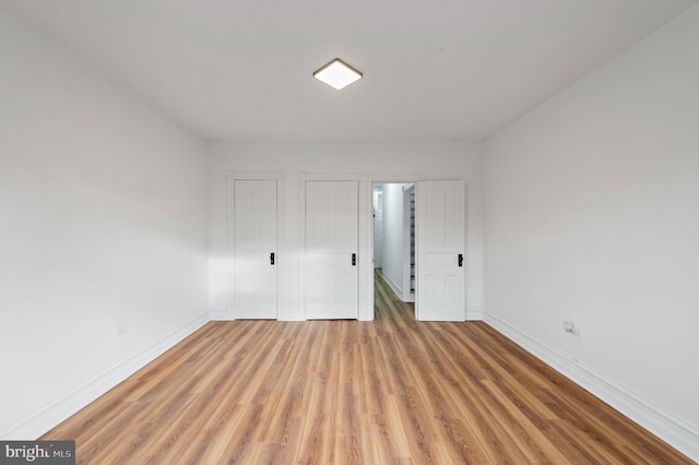 unfurnished bedroom with light wood-style flooring and baseboards