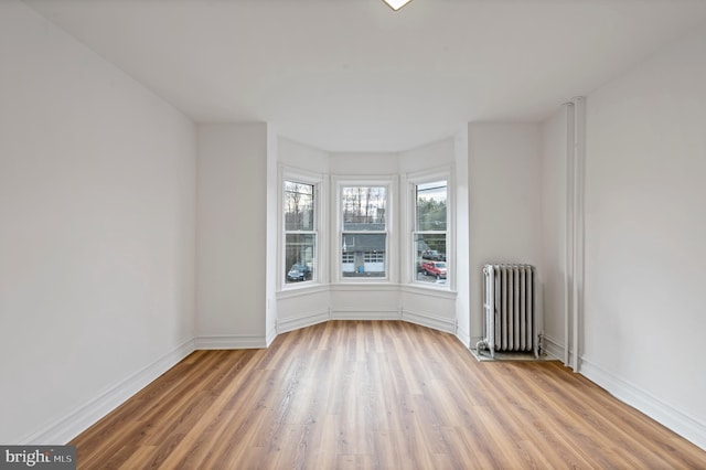 empty room featuring radiator, baseboards, and wood finished floors