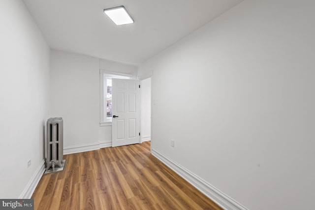 unfurnished room with baseboards, wood finished floors, and radiator