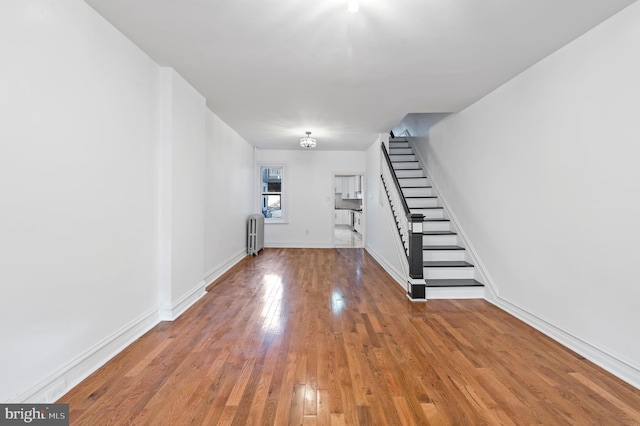 foyer entrance featuring radiator, baseboards, stairway, and hardwood / wood-style floors