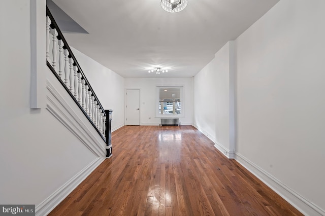 entryway with stairway, radiator heating unit, wood finished floors, and baseboards