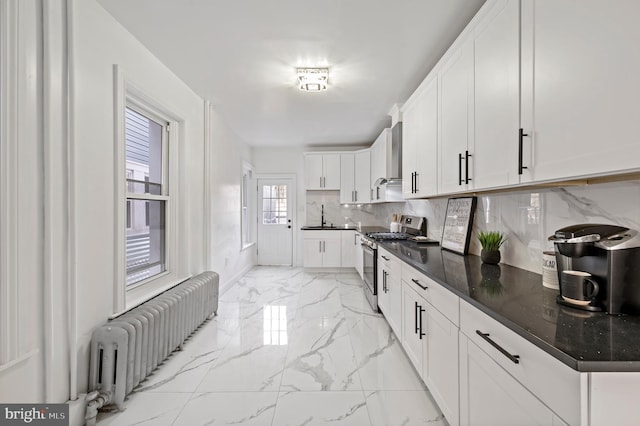 kitchen with white cabinets, marble finish floor, tasteful backsplash, radiator heating unit, and gas range