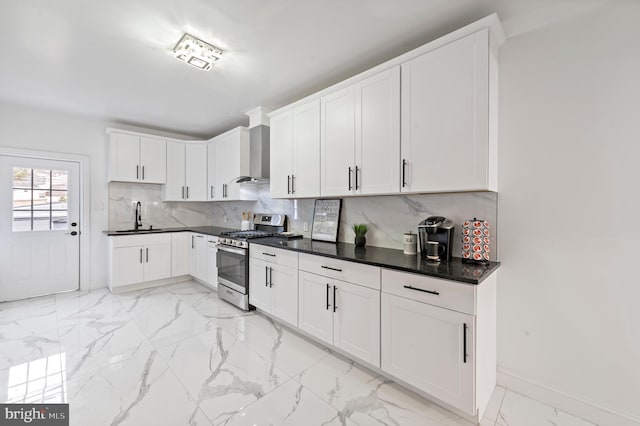 kitchen featuring wall chimney exhaust hood, a sink, marble finish floor, backsplash, and gas stove