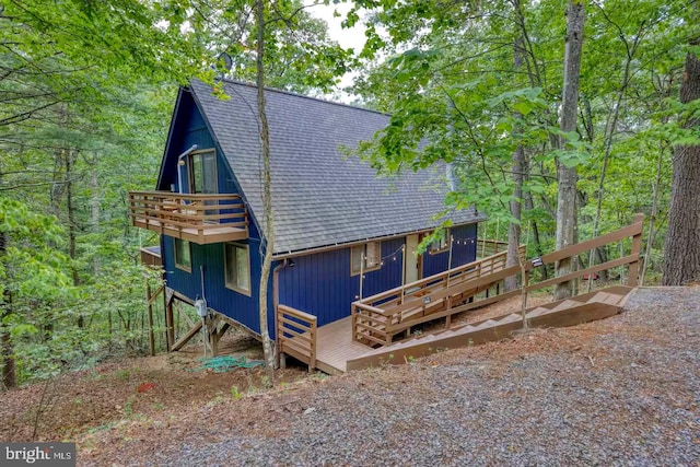 view of front of house featuring a balcony and a shingled roof