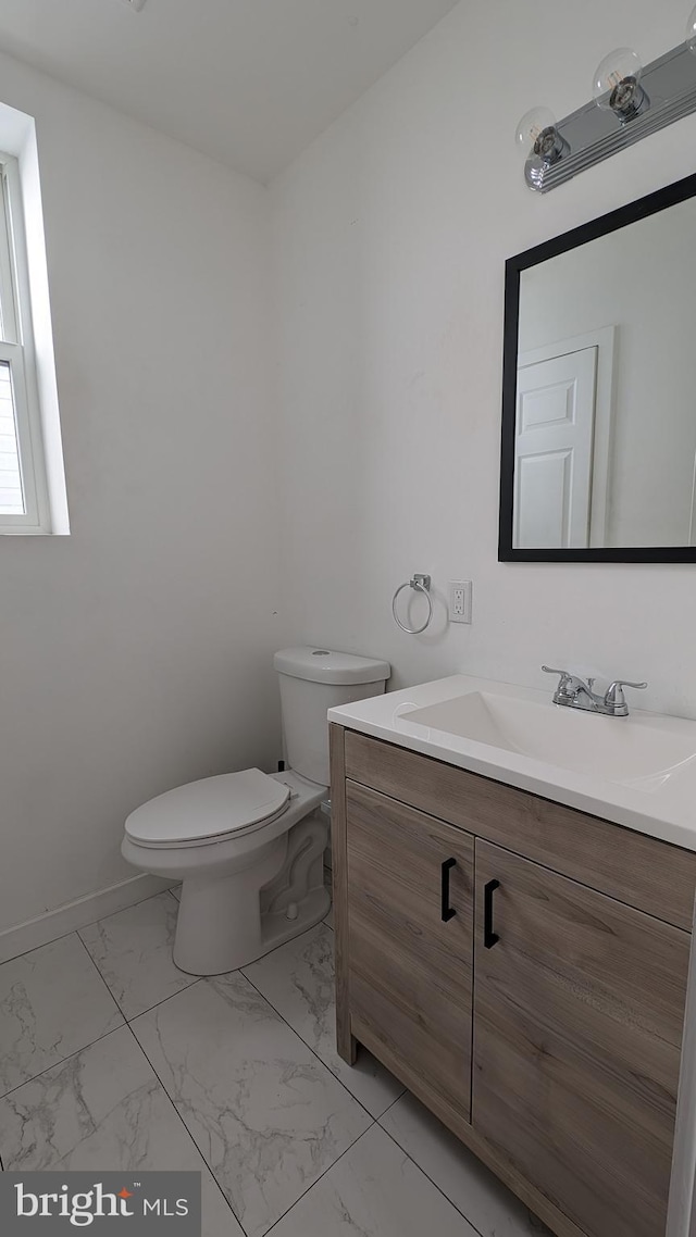 bathroom with marble finish floor, baseboards, vanity, and toilet