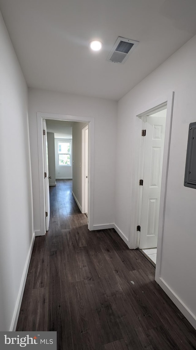 corridor featuring electric panel, visible vents, dark wood finished floors, and baseboards