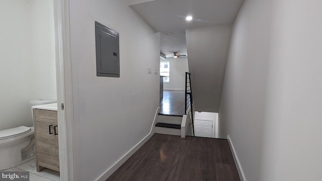 corridor featuring electric panel, baseboards, and wood finished floors