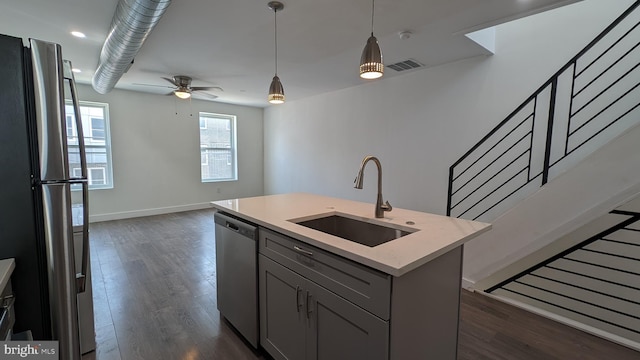 kitchen with hanging light fixtures, dark wood finished floors, stainless steel appliances, and a sink