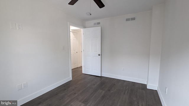 empty room with ceiling fan, dark wood-type flooring, visible vents, and baseboards