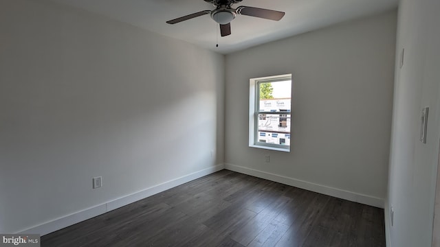 empty room with dark wood-style floors, a ceiling fan, and baseboards