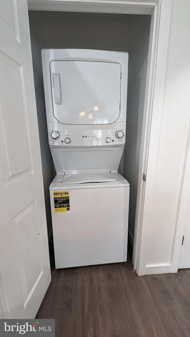 clothes washing area featuring laundry area, dark wood finished floors, and stacked washer and clothes dryer