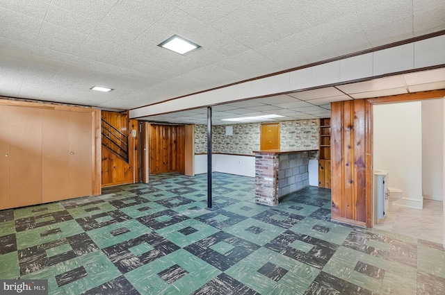 finished basement featuring a dry bar, wood walls, and tile patterned floors