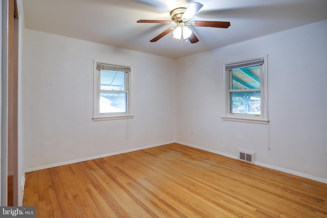 unfurnished room with light wood-style floors, baseboards, visible vents, and a ceiling fan