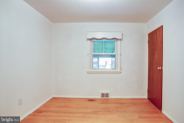 spare room with baseboards, visible vents, and wood finished floors