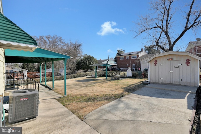 view of yard featuring an outbuilding, central AC, a storage unit, and fence