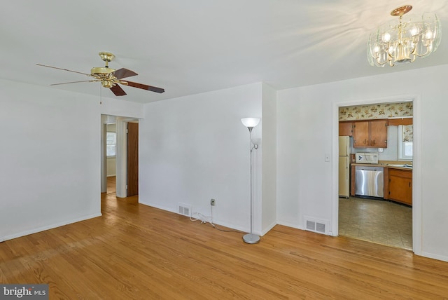 unfurnished living room featuring light wood-type flooring, visible vents, and ceiling fan with notable chandelier