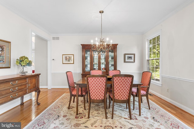 dining area with a chandelier, wood finished floors, crown molding, and baseboards
