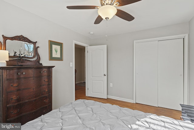 bedroom with a ceiling fan, wood finished floors, a closet, and baseboards