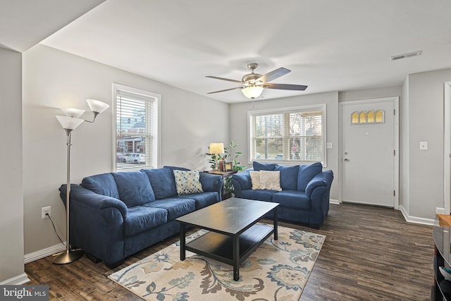 living area featuring baseboards, a healthy amount of sunlight, and dark wood finished floors