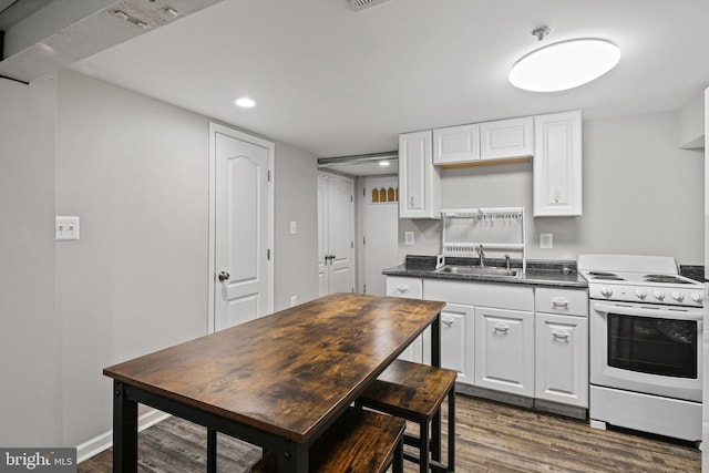 kitchen with white range with electric cooktop, a sink, dark countertops, white cabinetry, and dark wood-style flooring