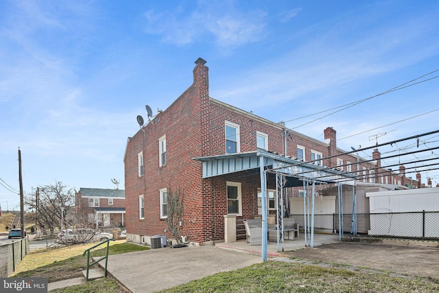 back of house featuring a patio, fence, central AC, entry steps, and brick siding