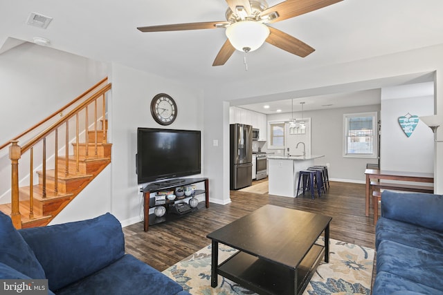 living room featuring visible vents, stairs, baseboards, and wood finished floors