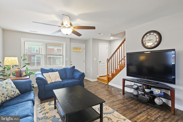 living room with stairway, baseboards, visible vents, and wood finished floors