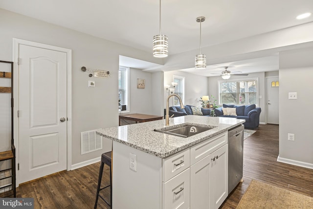 kitchen with visible vents, a kitchen island with sink, a sink, dishwasher, and dark wood-style flooring