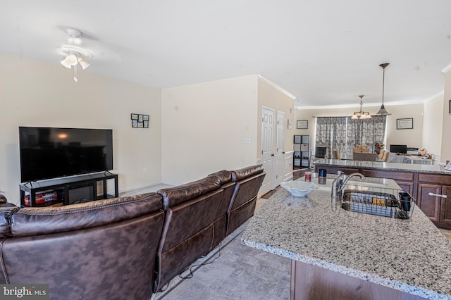 living area featuring crown molding and ceiling fan with notable chandelier