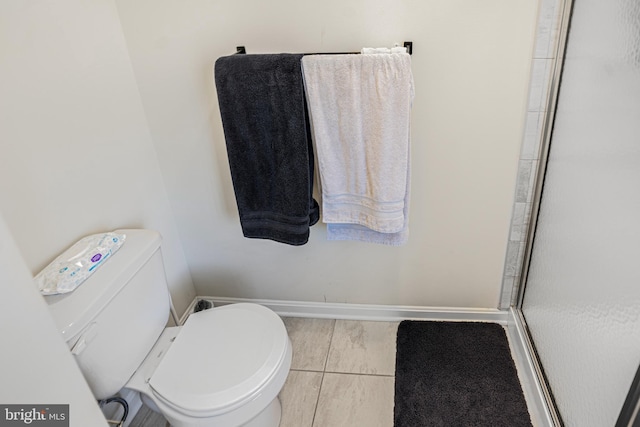 full bathroom featuring baseboards, a shower stall, and toilet