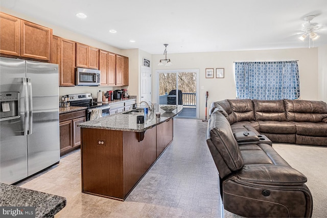 kitchen featuring dark stone counters, stainless steel appliances, a breakfast bar area, and open floor plan