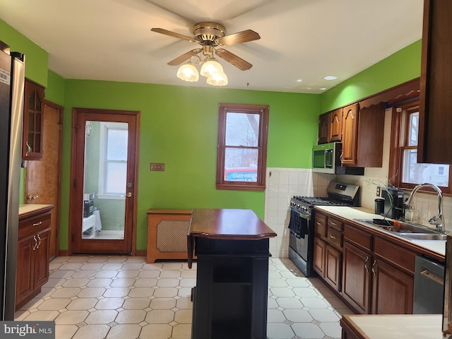 kitchen featuring light countertops, appliances with stainless steel finishes, a sink, and a ceiling fan