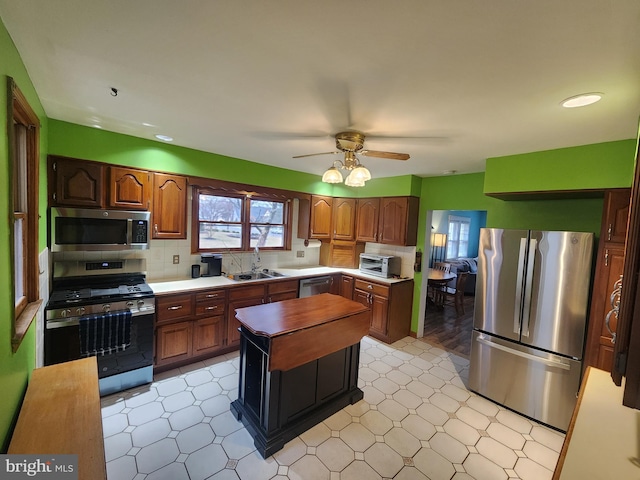 kitchen featuring stainless steel appliances, a sink, decorative backsplash, and light floors