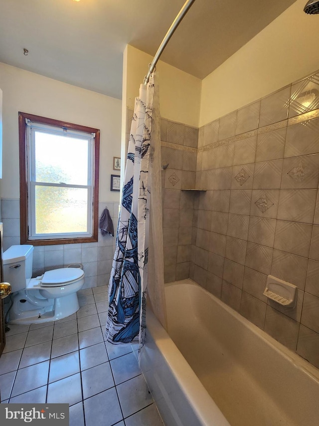 full bathroom featuring tile walls, shower / bath combination with curtain, toilet, wainscoting, and tile patterned floors