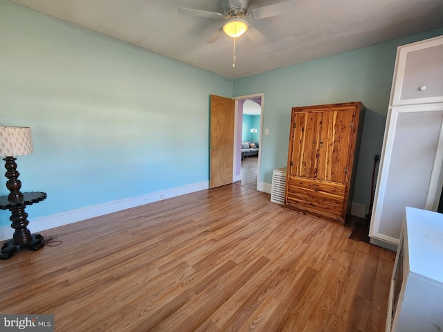 unfurnished bedroom featuring light wood-style floors, baseboards, and a ceiling fan