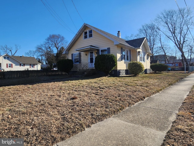 view of front facade featuring a chimney, fence, and a front yard